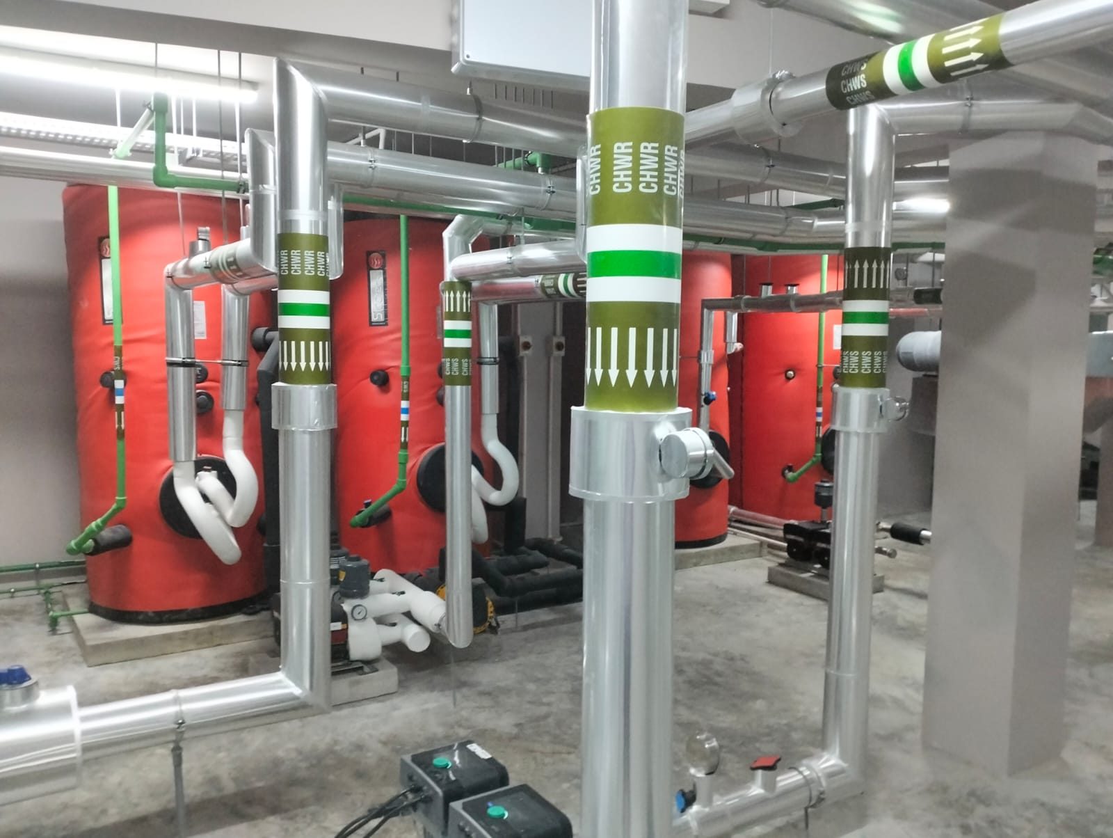 Chilled-water plant room with colour-coded CHWS and CHWR pipework, buffer vessels and inline pumps