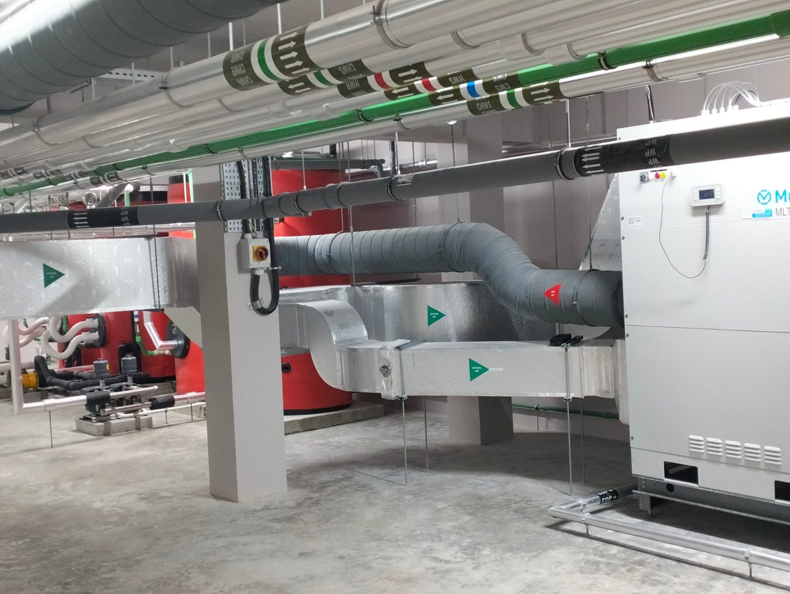 Insulated chilled-water and heating pipework, spiral ductwork and air-handling units in a completed mechanical plant room