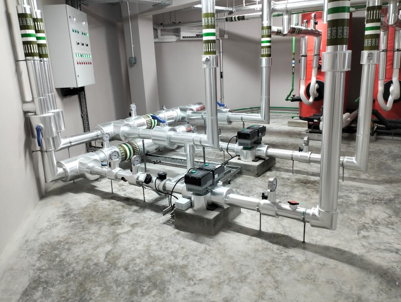 Chilled-water pump room with insulated piping, inline pumps and red buffer vessels
